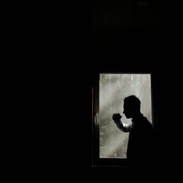 Silhouette of a person meditating against a simple background.